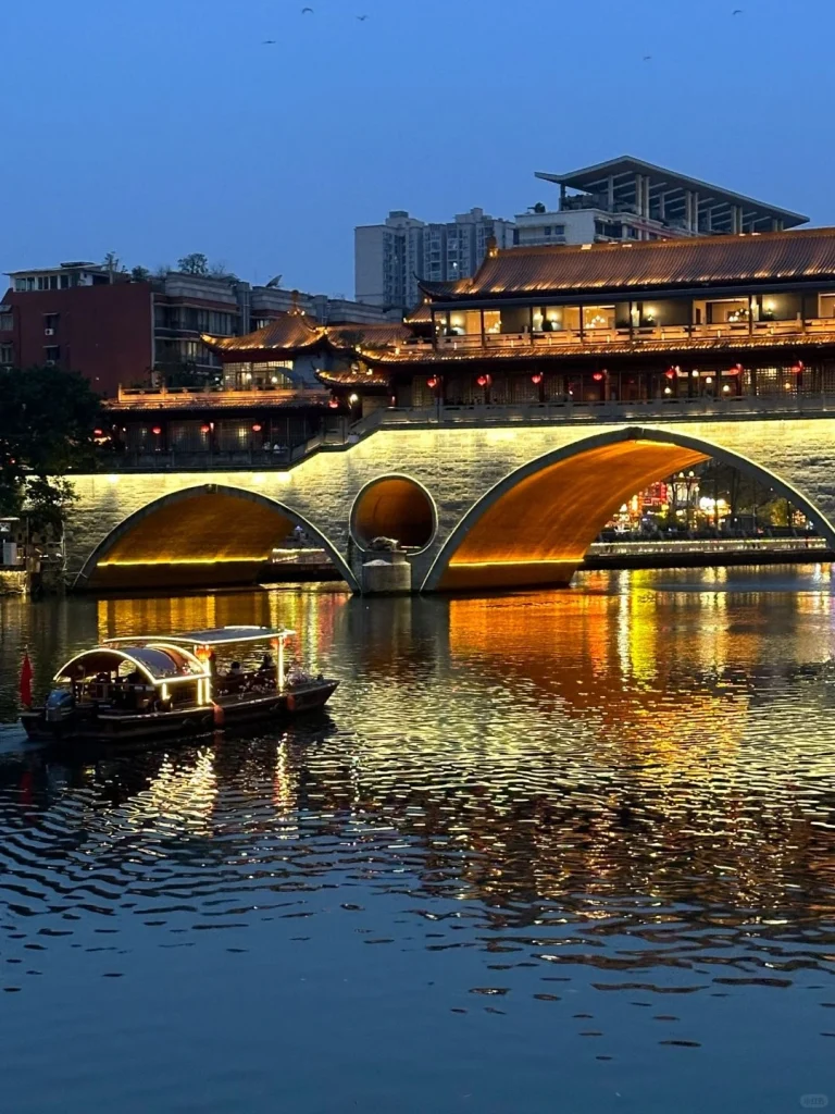 An evening shot of Anshun Bridge reflecting its golden lights on the Jin River in Chengdu