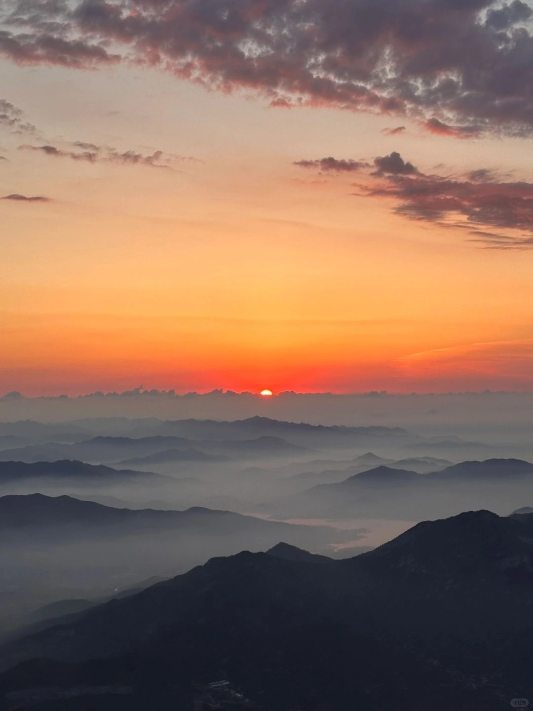 Beautiful sunrise over layered mountain ranges from the peak of Mount Tai with soft colors in the sky