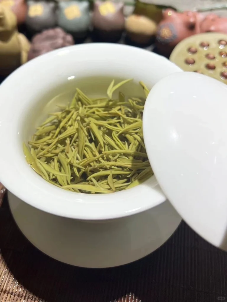 A gaiwan filled with steeping Duyun Maojian tea leaves showcasing its vibrant green hue and delicate aroma