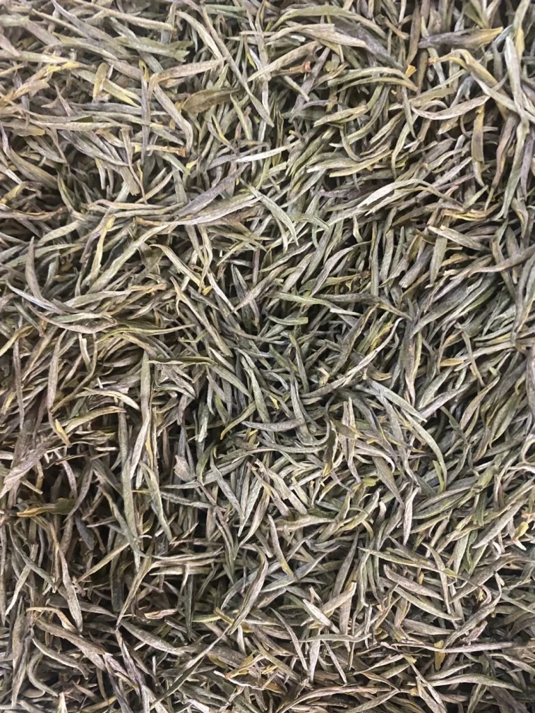 A pile of dried Junshan Yinzhen tea leaves highlighting its unique texture and quality