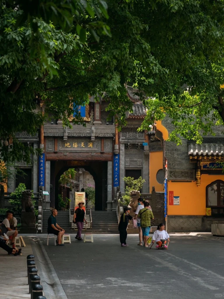Chongqings ancient temple gate surrounded by green trees with people strolling nearby