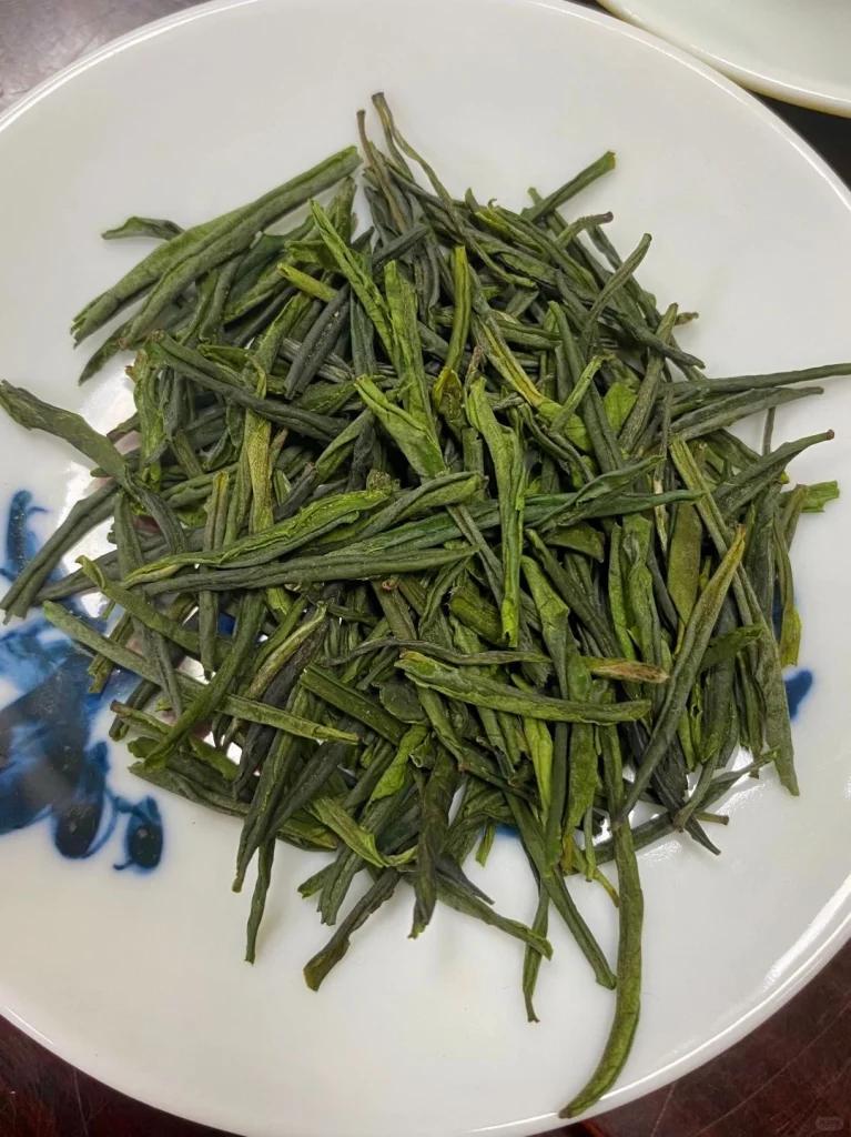 Close up of premium Luan Guapian tea leaves displayed on a white plate