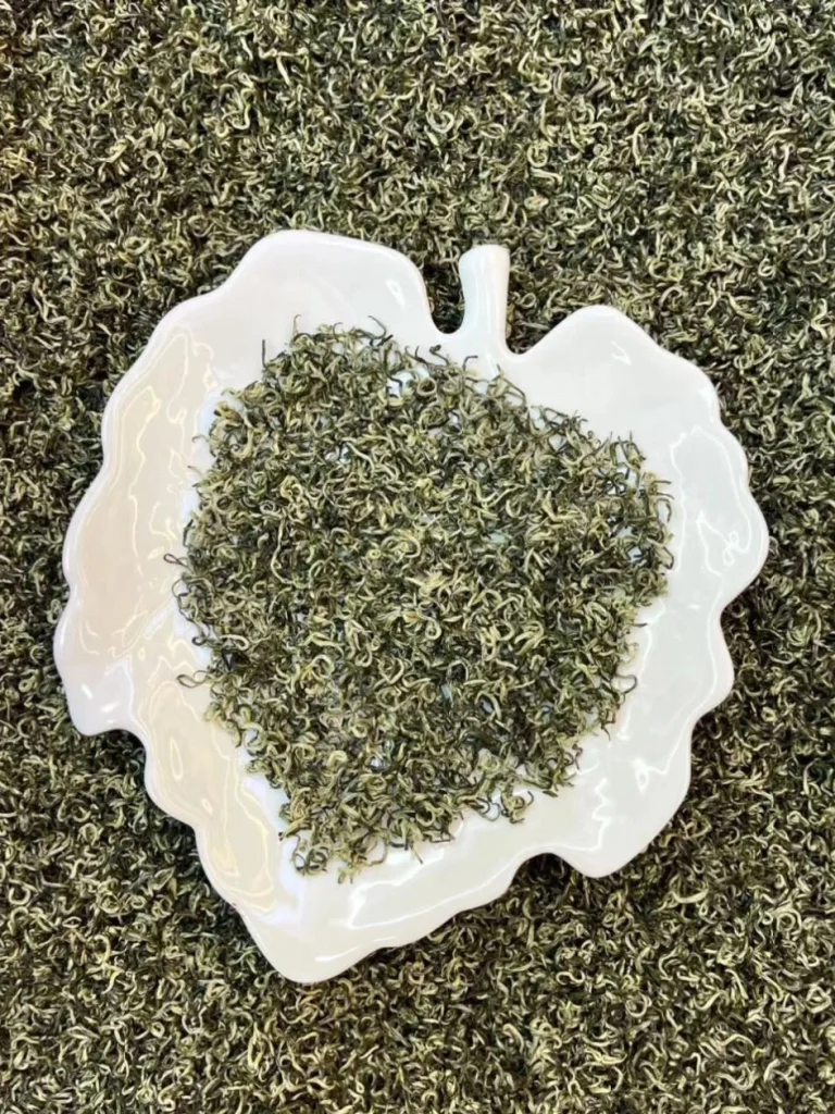 Dried Biluochun tea leaves displayed on a decorative white plate