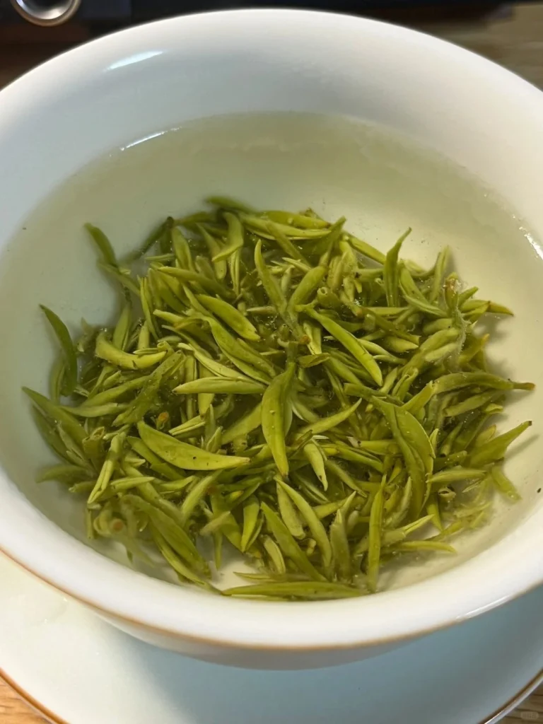 Freshly brewed Biluochun green tea leaves floating in a white ceramic cup