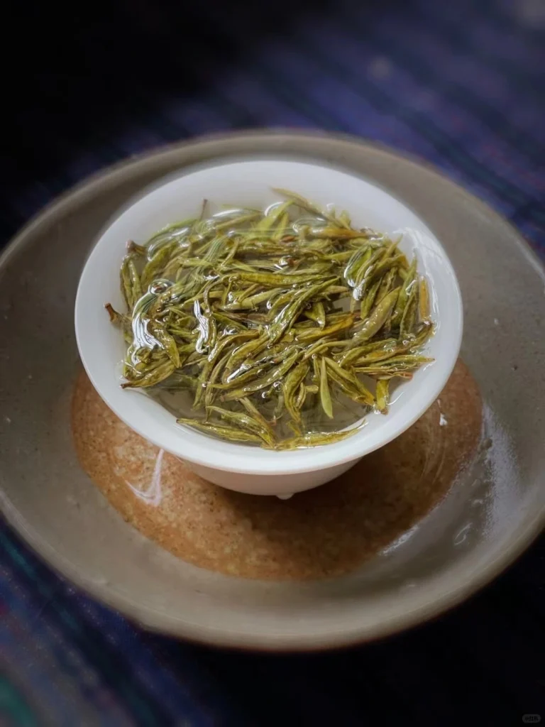 Freshly brewed Junshan Yinzhen tea leaves floating in water in a porcelain gaiwan