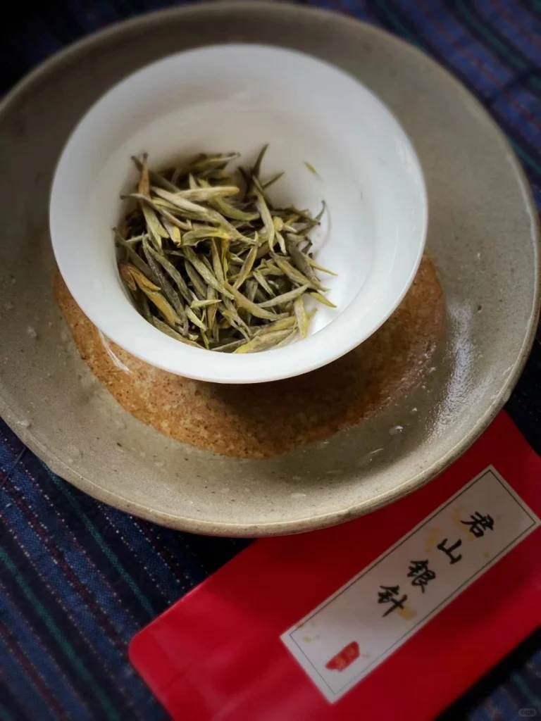 Junshan Yinzhen tea leaves elegantly arranged in a traditional white porcelain bowl
