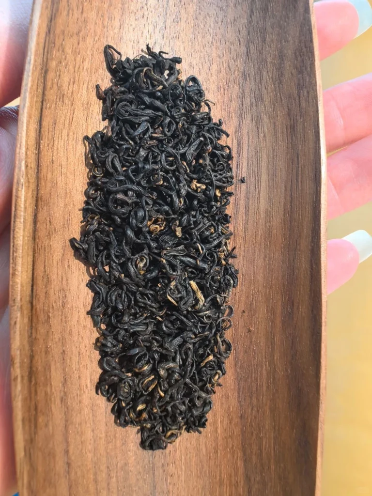 Keemun black tea leaves displayed on a wooden serving tray under natural light