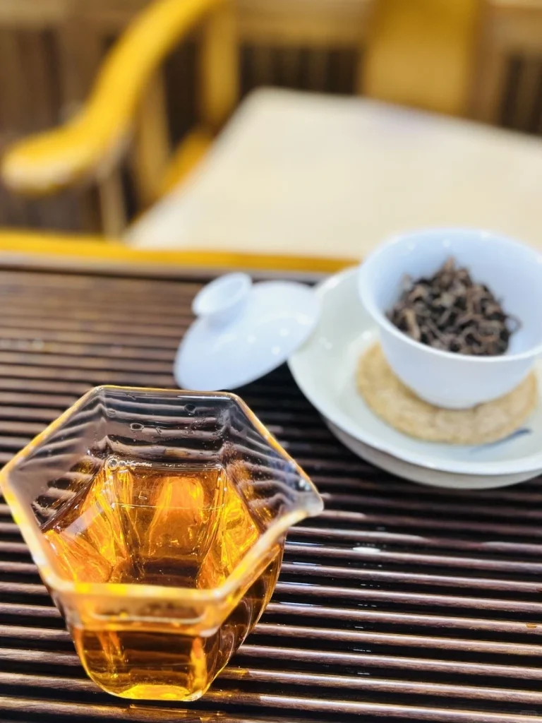Keemun black tea served in a hexagonal glass cup on a bamboo tea table