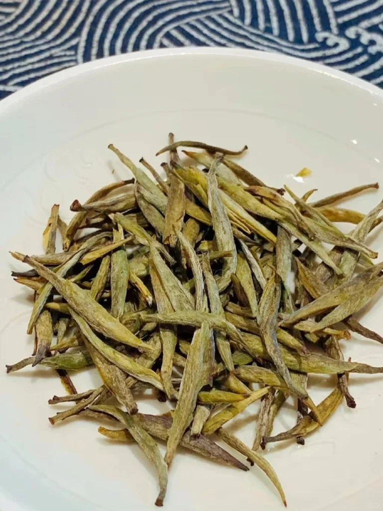 Plate of Junshan Yinzhen tea leaves with a vibrant and natural appearance