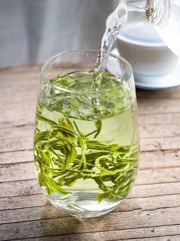 Pouring hot water into a glass with fresh Biluochun tea leaves