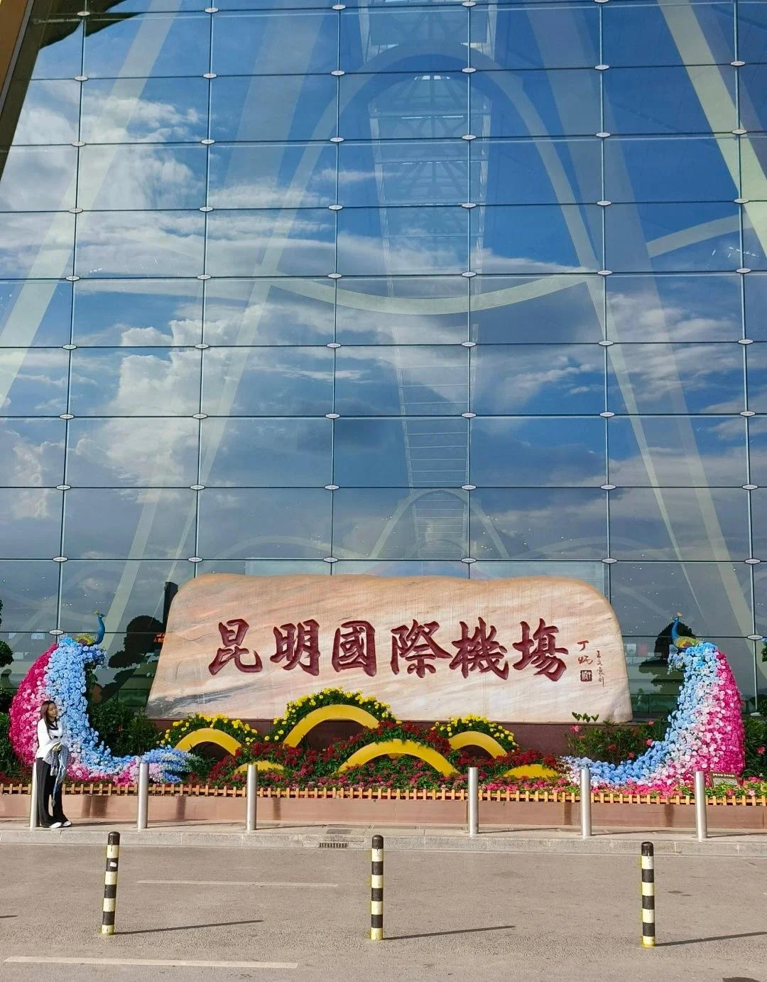A entrada principal do Aeroporto Internacional de Kunming Changshui com uma grande placa decorativa e arranjos florais - Onde ficar em Kunming: Melhores áreas e hotéis em 2026 - The China Journey A entrada principal do Aeroporto Internacional de Kunming Changshui com uma grande placa decorativa e arranjos florais - Onde ficar em Kunming: Melhores áreas e hotéis em 2026 - The China Journey