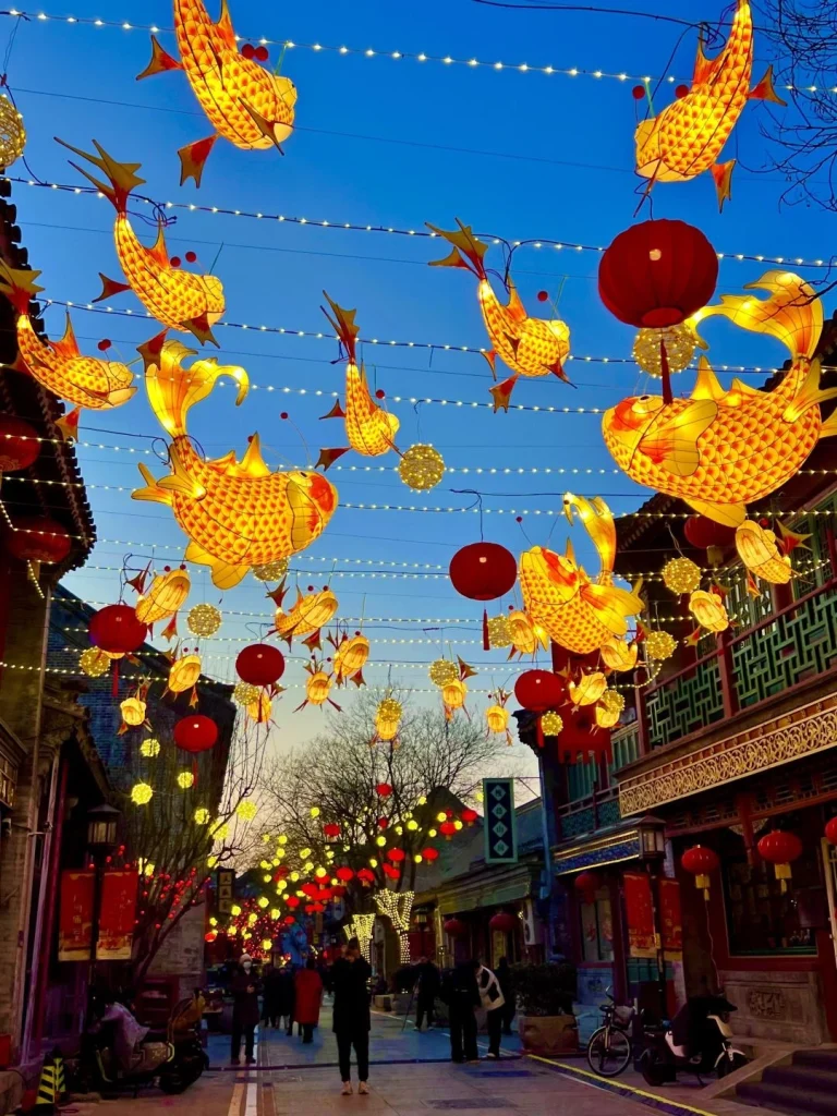 Street decorated with glowing fish shaped lanterns and red Chinese lanterns during a Beijing festival