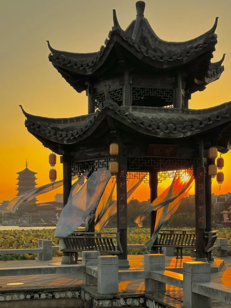 Sunset Pavilion at Yanghu Wetland Park Changsha A traditional Chinese pavilion in Yanghu Wetland Park Changsha draped with flowing fabric illuminated by a breathtaking sunset