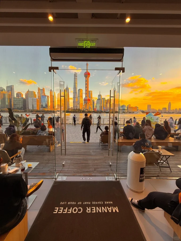 Sunset view of Shanghai skyline from a café A breathtaking sunset view of the Shanghai skyline captured from the entrance of Manner Coffee with people enjoying the scenery