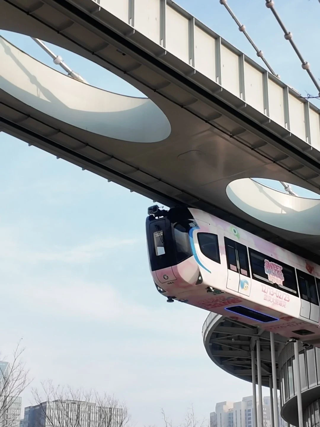 Tren aéreo de Wuhan en movimiento: Un moderno tren monorraíl suspendido que recorre la ciudad de Wuhan, mostrando un transporte urbano futurista. Cómo moverse por Wuhan: La mejor guía de transporte de 2026 - The China Journey Tren aéreo de Wuhan en movimiento: Un moderno tren monorraíl suspendido que recorre la ciudad de Wuhan, mostrando un transporte urbano futurista. Cómo moverse por Wuhan: La mejor guía de transporte de 2026 - The China Journey