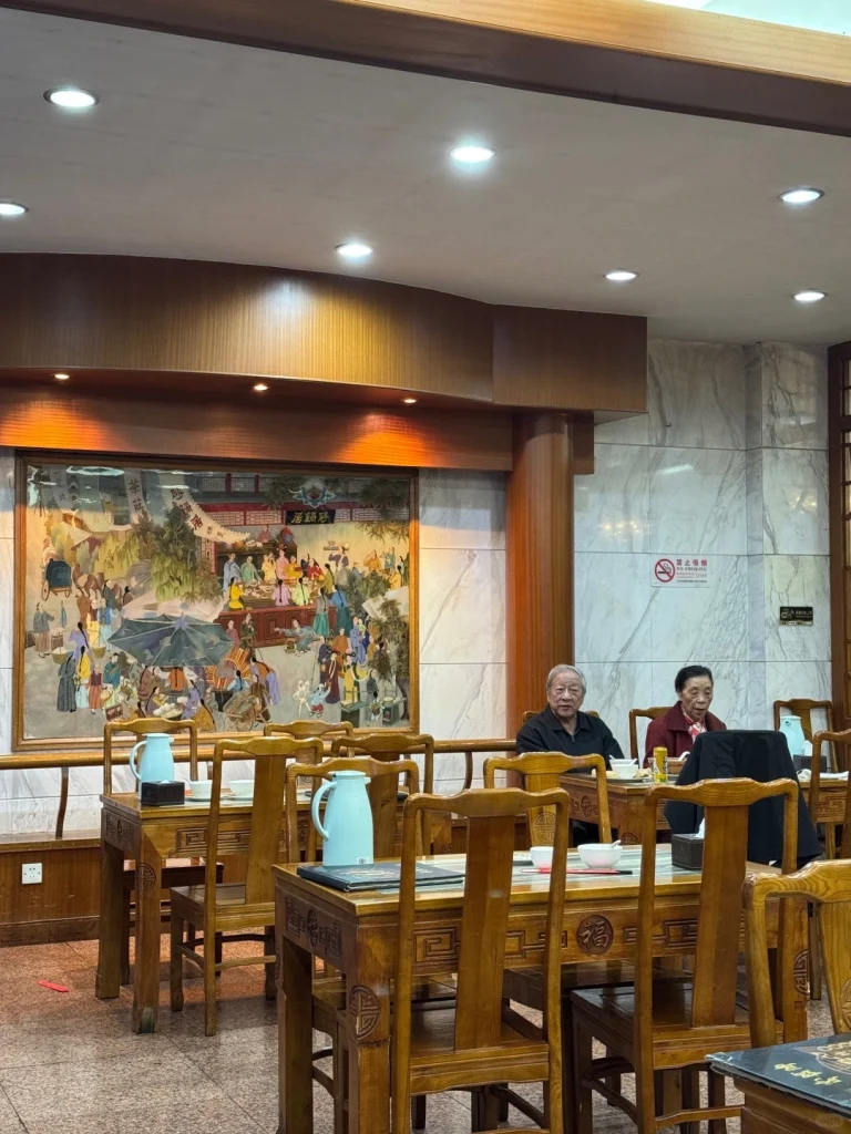 A traditional dining atmosphere at Shaguoju Traditional Chinese style seating with paintings and customers enjoying their meal at Shaguoju restaurant in Beijing