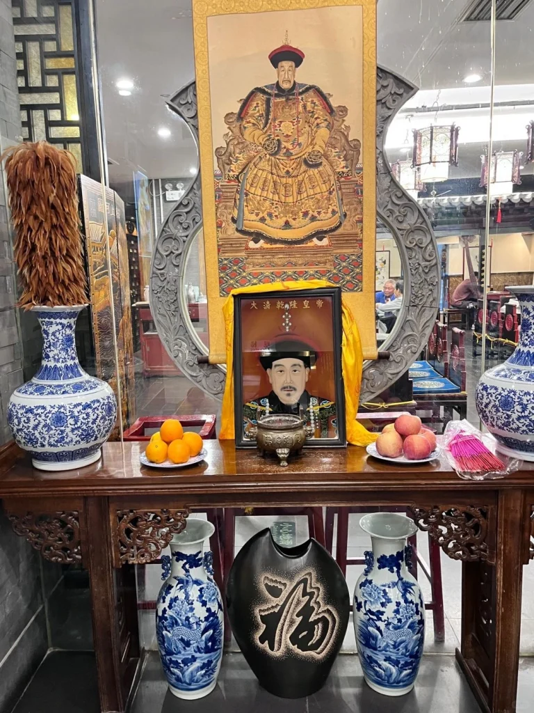 A traditional scene at Du Yi Chu restaurant in Beijing with historical portraits of Qing Dynasty figures displayed alongside decorative furnishings