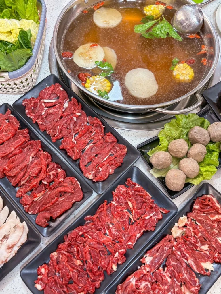Chaozhou Beef Hotpot Experience A table of neatly sliced beef vegetables and meatballs surrounding a simmering broth