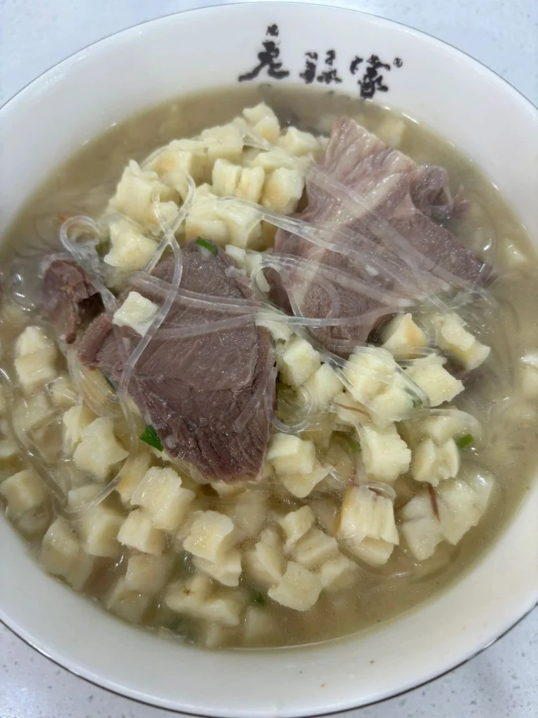 Close up of lamb noodles from Laosunjia Restaurant served in a traditional bowl with clear broth