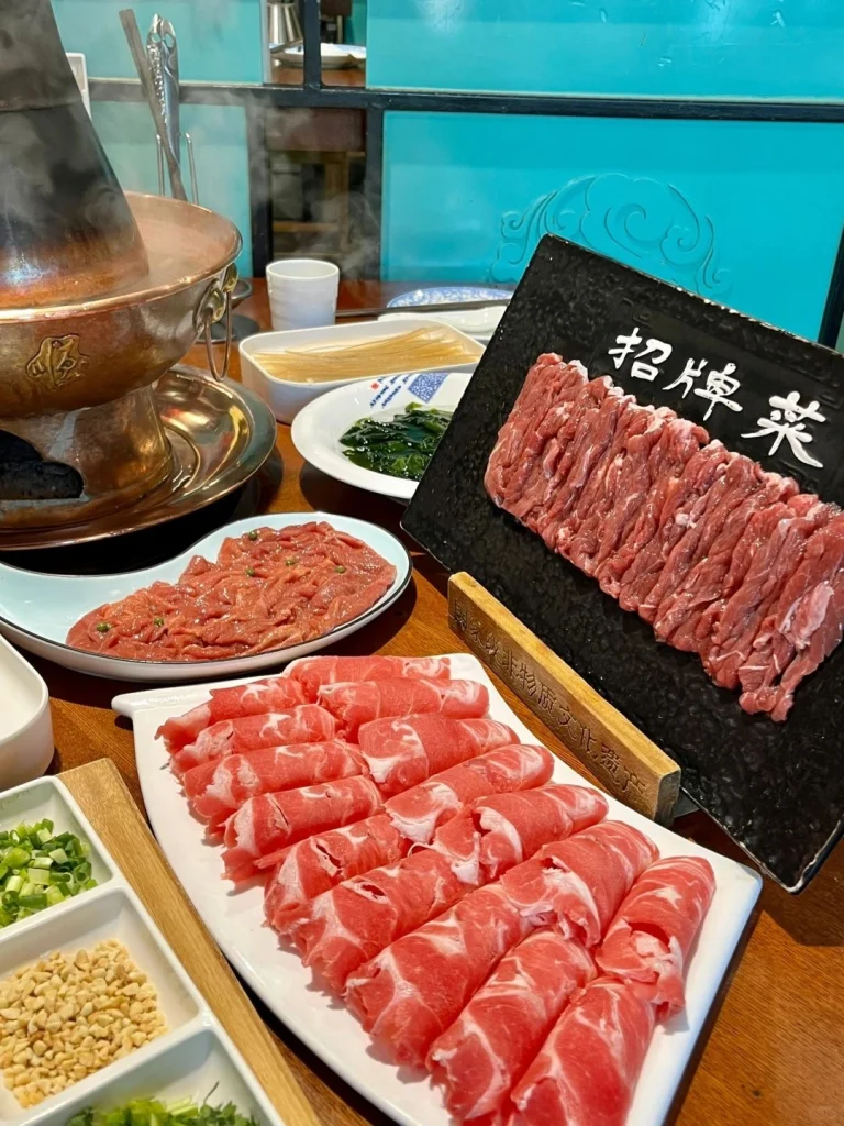 Copper pot hot pot at Dong Lai Shun An elegant setup with fresh ingredients like meats vegetables and dipping sauces ready to be cooked in the steaming pot
