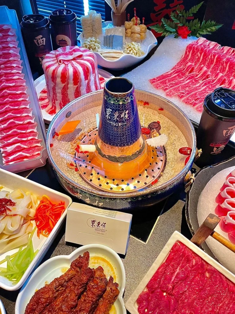 Dong Lai Shun hot pot A close up of fresh beef slices and vegetables ready to be dipped in the copper pot surrounded by traditional dishes and sauces