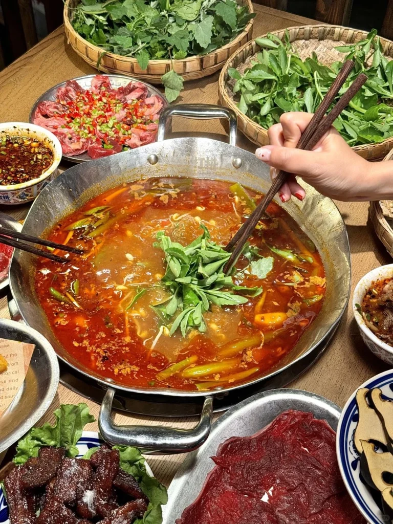 Enjoying Guizhou Sour Soup Hot Pot Hand picking ingredients into the flavorful soup