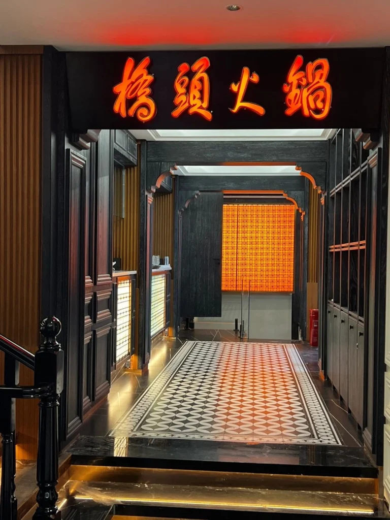 Entrance to a vibrant hotpot restaurant with a glowing 桥头火锅 sign and a luxurious interior design