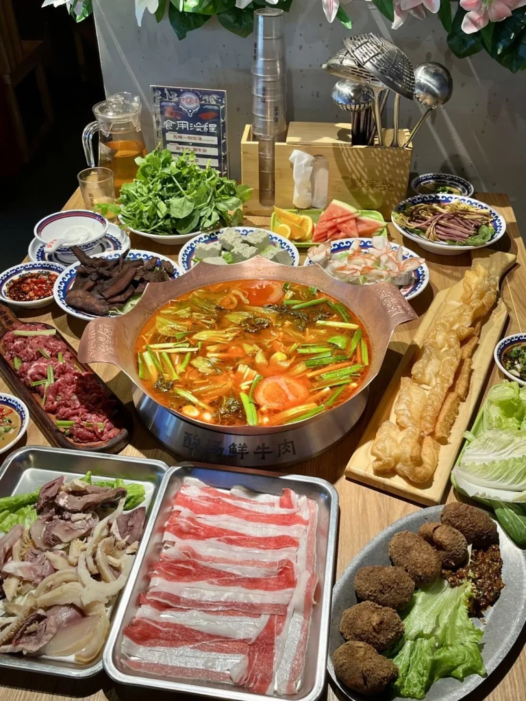Guizhou Sour Soup Hot Pot Feast An array of ingredients surrounding the copper hot pot