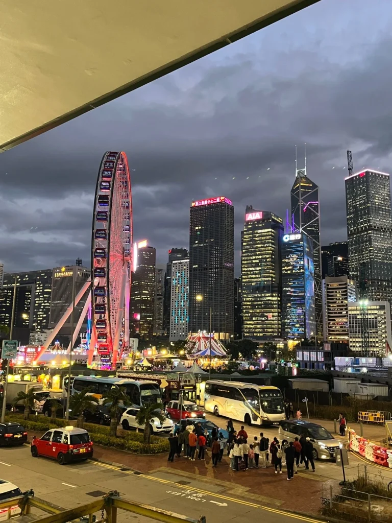 Hong Kong Ferris wheel at night Vibrant night scene of Hong Kongs Ferris wheel illuminated with city lights and skyscrapers in the background