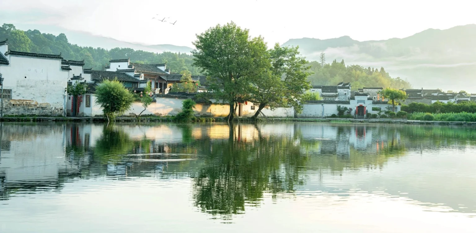 Aldea de Hong en Anhui. Una vista apacible de la aldea de Hong en Anhui, con aguas cristalinas que reflejan la arquitectura tradicional de estilo Huizhou y exuberantes montañas verdes al fondo. Anhui, cuna de la cultura taoísta y la ópera de Anhui 2026. El viaje a China. Provincias de China. Descubre la cultura y el patrimonio regional. El viaje a China. Aldea de Hong en Anhui. Una vista apacible de la aldea de Hong en Anhui, con aguas cristalinas que reflejan la arquitectura tradicional de estilo Huizhou y exuberantes montañas verdes al fondo. Anhui, cuna de la cultura taoísta y la ópera de Anhui 2026. El viaje a China. Provincias de China. Descubre la cultura y el patrimonio regional. El viaje a China.