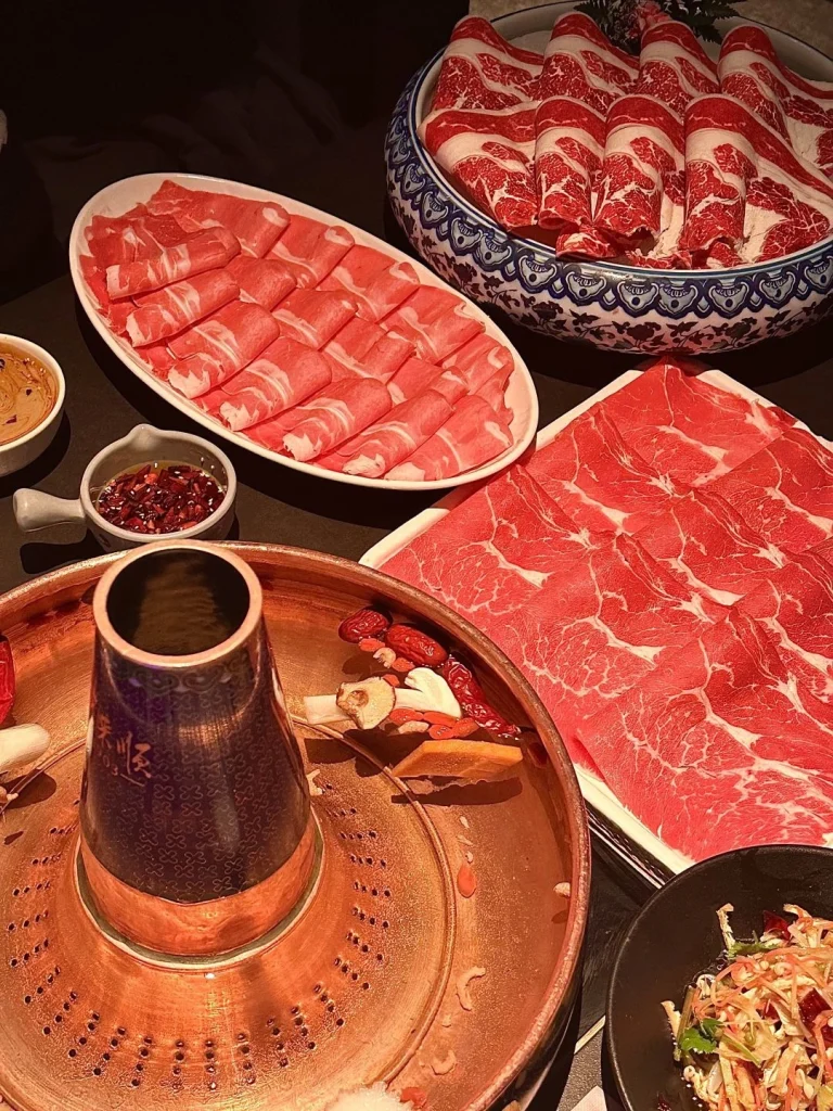 Hot pot dining experience at Dong Lai Shun Close up of the copper pot fresh vegetables and meats with the restaurants vibrant decor in the background