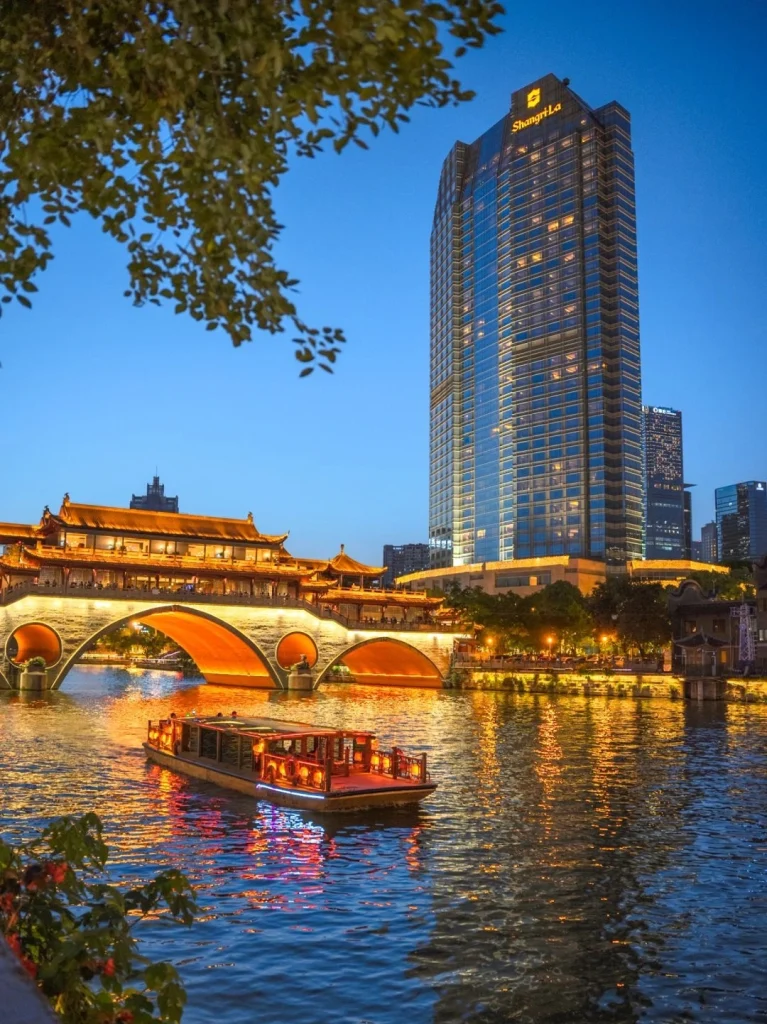 Night view of a bridge and river in Chengdu The brightly lit Jinjiang River and historic bridge in Chengdu with modern skyscrapers in the backdrop