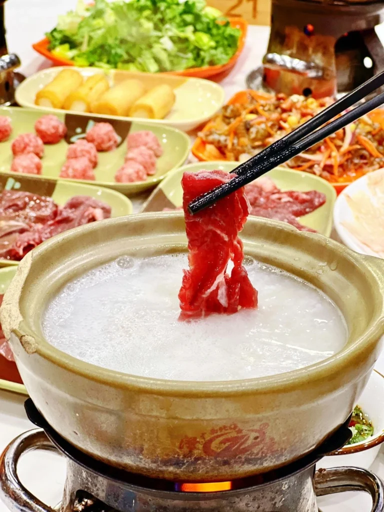 Shunde congee hotpot with fresh ingredients such as seafood vegetables and meats being served in a bubbling broth