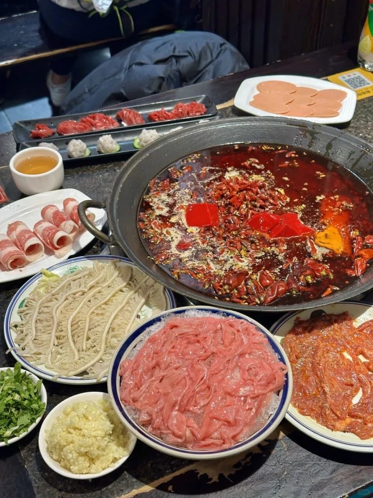 Sichuan Hotpot with various fresh ingredients including meats vegetables and noodles in a spicy broth