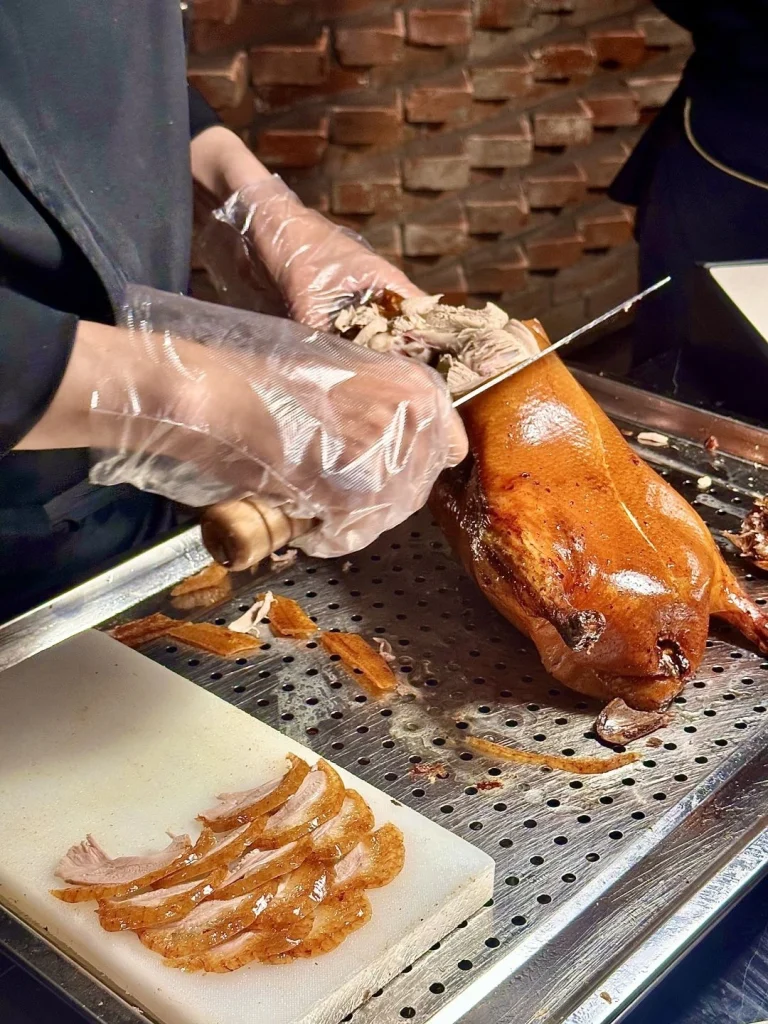 Slicing Peking Duck at Quan Jude Beijing Chef carving Peking Duck at Quan Jude restaurant in Beijing showcasing the crisp skin and tender meat