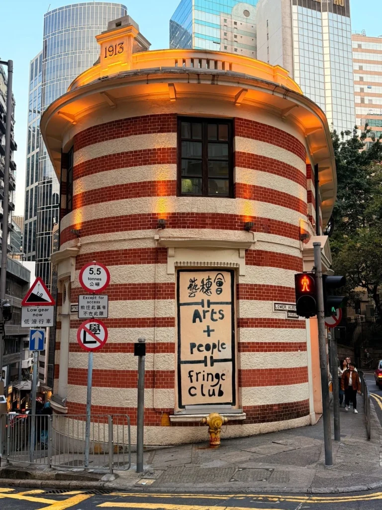 The round shaped Fringe Club building with the Arts + People signage in the bustling area of Hong Kong