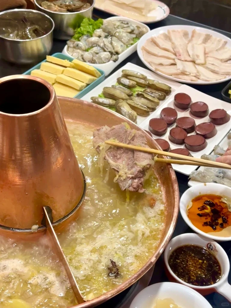 Traditional Northeast Hot Pot Pork slices and side dishes around the copper pot