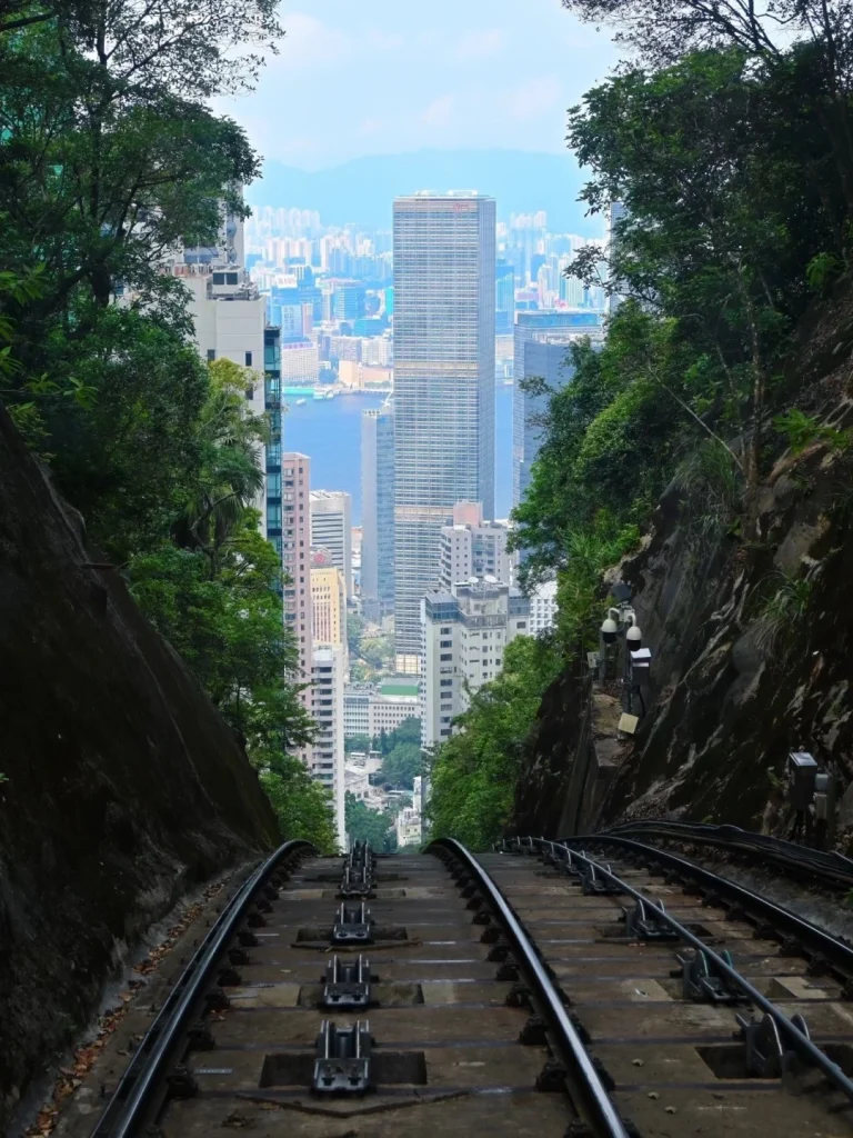 View of the Peak Tram tracks and city skyline Aerial view of Hong Kongs Peak Tram tracks winding through lush greenery with towering skyscrapers in the background