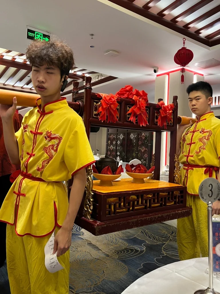 Yellow clad staff at Juchun Garden Two young staff members in traditional yellow clothing carrying a decorative tray with red ribbons in Juchun Garden Fuzhou