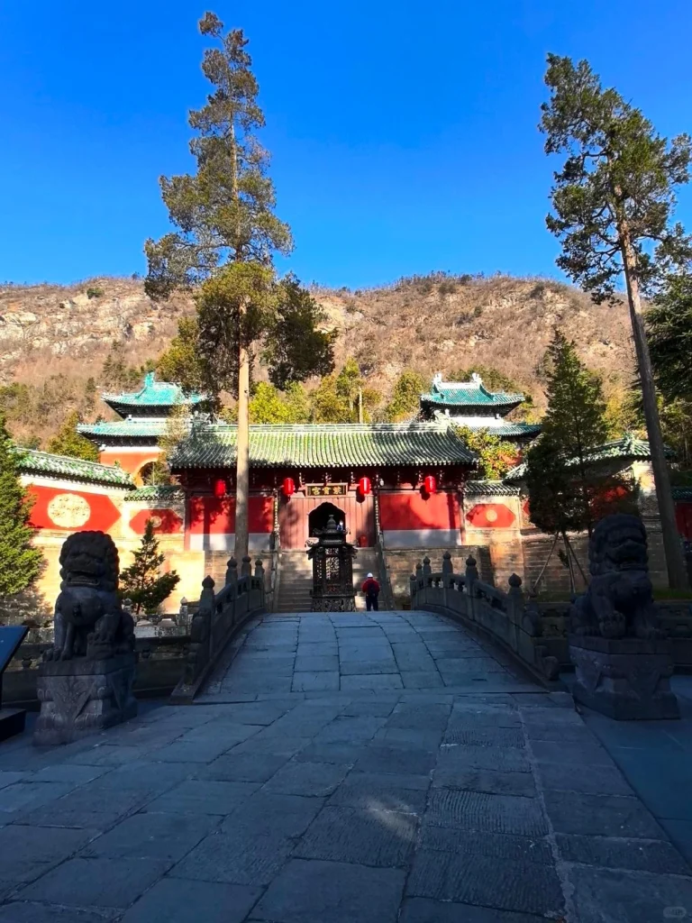Entrance to Wudang temple with red walls stone lions and mountain backdrop