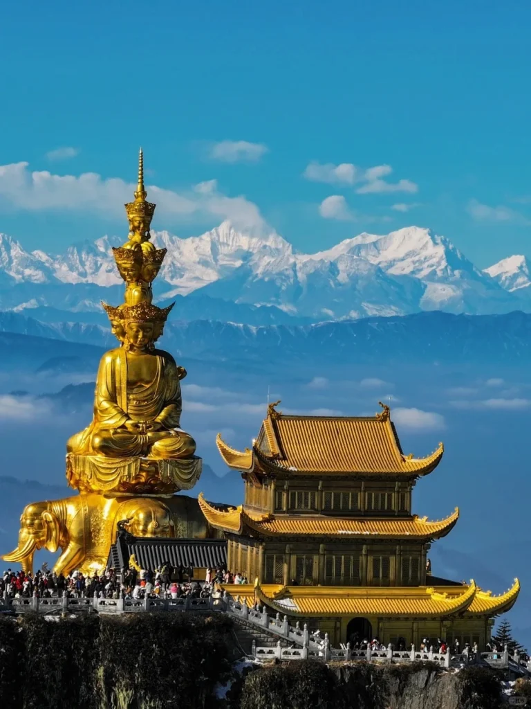 Golden statue and temple of Mount Emei with snowy Himalayan mountains in background