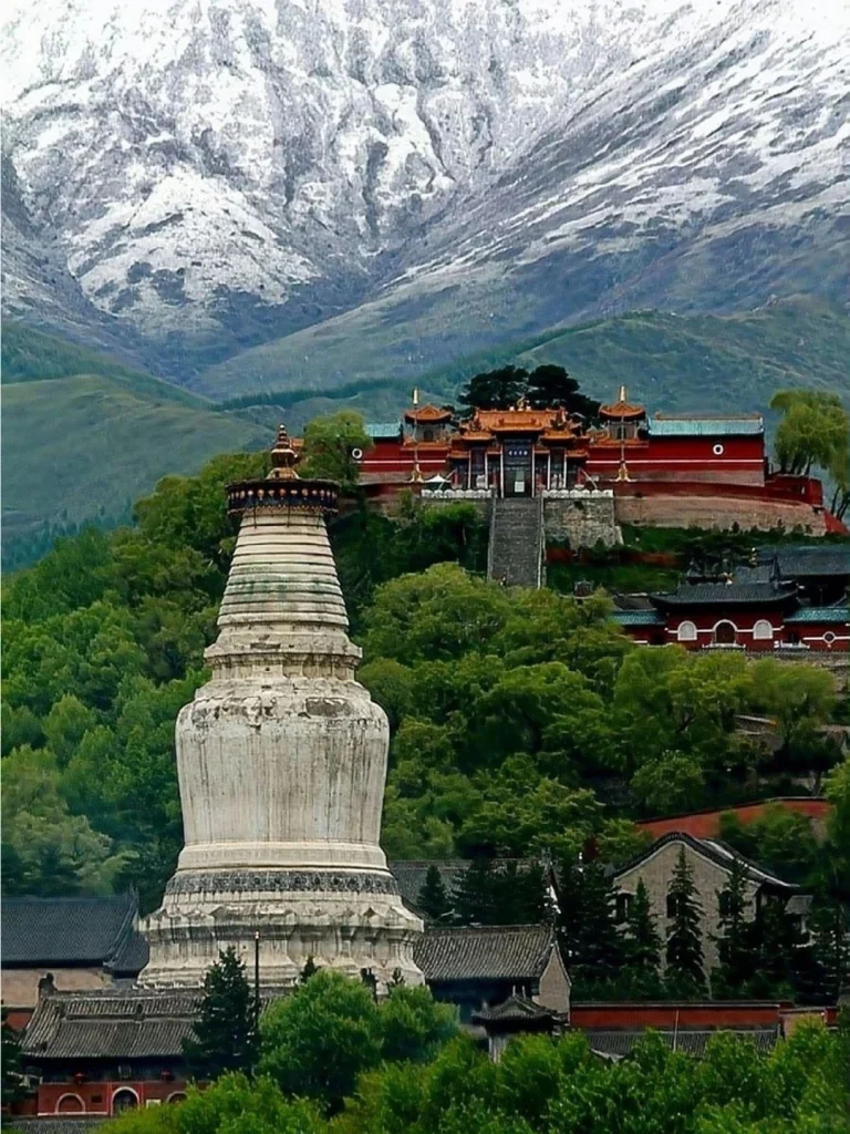 Mount Wutai Shanxi Snowy mountain backdrop with ancient white pagoda and temple complex nestled in green forest