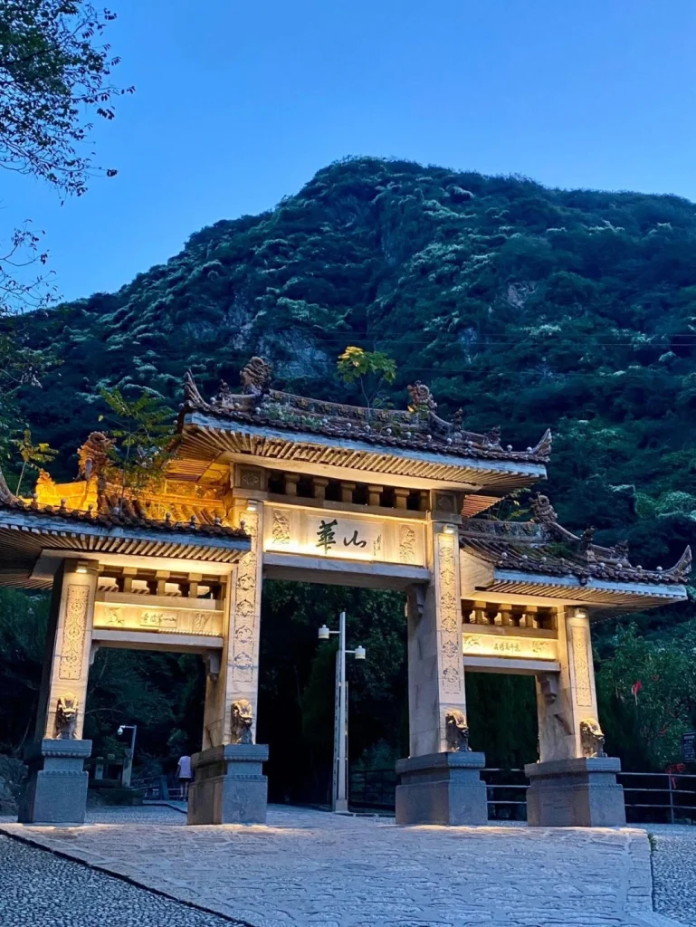 Nighttime view of the entrance gate to Huashan with mountain backdrop illuminated in soft light