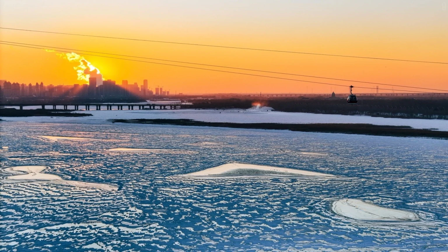 Atardecer sobre el río Songhua Hermoso atardecer sobre el río Songhua en Harbin con un teleférico pasando sobre el agua helada y el horizonte de la ciudad al fondo - Heilongjiang, Mejor Destino Turístico de Hielo y Nieve de China 2026 - El Viaje a China - Provincias de China - Descubre la Cultura y el Patrimonio Regional - El Viaje a China Atardecer sobre el río Songhua Hermoso atardecer sobre el río Songhua en Harbin con un teleférico pasando sobre el agua helada y el horizonte de la ciudad al fondo - Heilongjiang, Mejor Destino Turístico de Hielo y Nieve de China 2026 - El Viaje a China - Provincias de China - Descubre la Cultura y el Patrimonio Regional - El Viaje a China