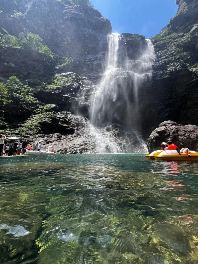 Waterfall and Kayaking in Lushan Tourists kayaking near a powerful mountain waterfall plunging into a clear pool in Lushan