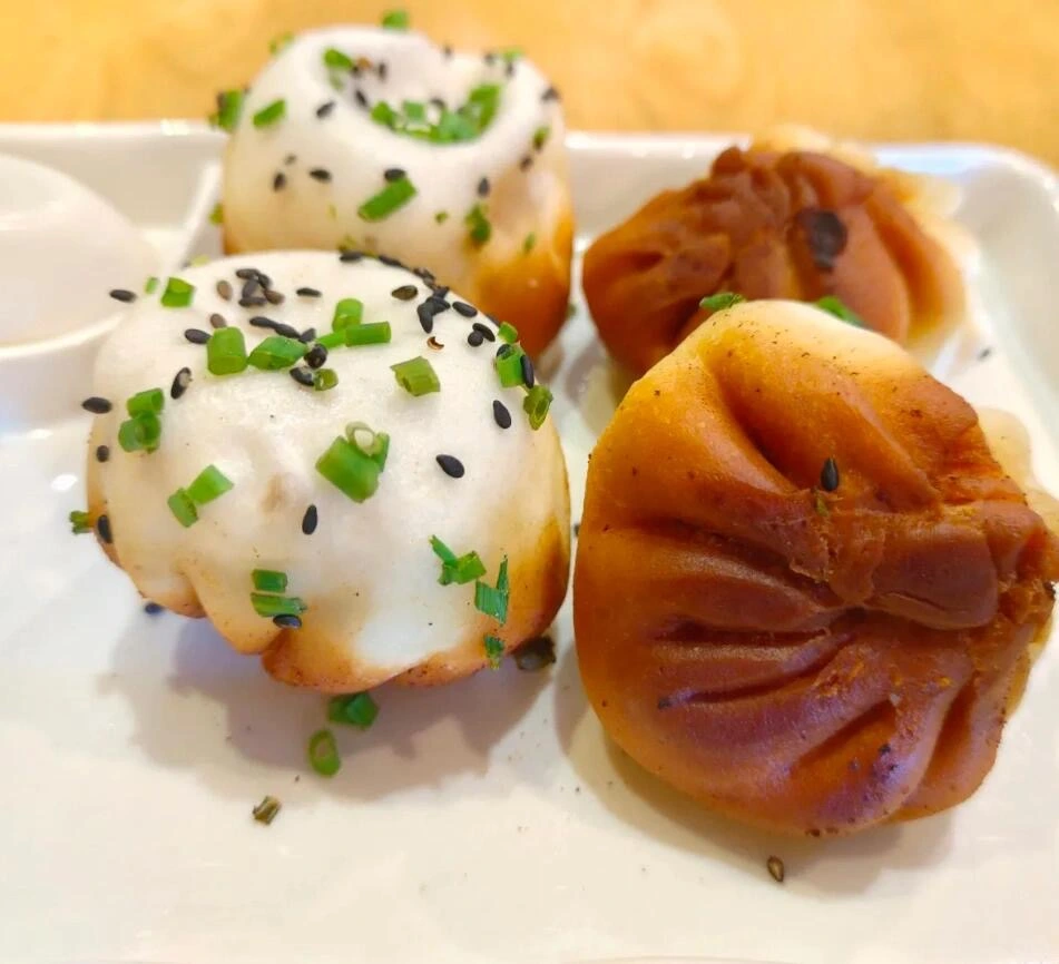 Gebakken Shengjian Bao in Shanghai – Krokante broodjes met varkensvlees, belegd met lente-uitjes en sesamzaadjes, vers geserveerd op een wit bord in Shanghai. - Wat is het populairste gerecht in Shanghai, China? 2026 - De reis door China Gebakken Shengjian Bao in Shanghai – Krokante broodjes met varkensvlees, belegd met lente-uitjes en sesamzaadjes, vers geserveerd op een wit bord in Shanghai. - Wat is het populairste gerecht in Shanghai, China? 2026 - De reis door China