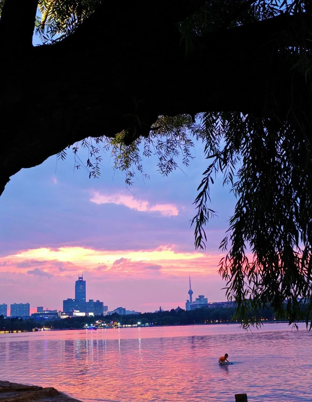 Zonsondergang boven een meer in Changchun met een kajakker en de skyline van de stad op de achtergrond - Reisgids Changchun: geschiedenis, parken & tips 2026 - The China Journey Zonsondergang boven een meer in Changchun met een kajakker en de skyline van de stad op de achtergrond - Reisgids Changchun: geschiedenis, parken & tips 2026 - The China Journey
