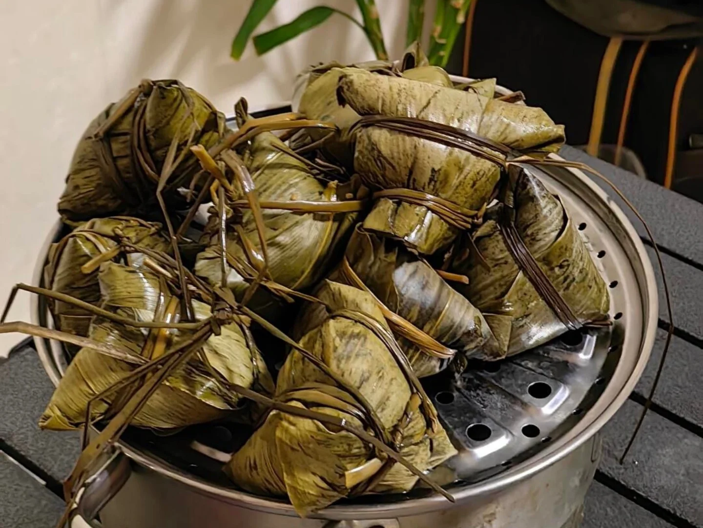 Gestoomde piramide Zongzi vastgebonden met gras – vers gekookte traditionele Chinese rijstdumplings gestapeld in een bamboe stoommandje