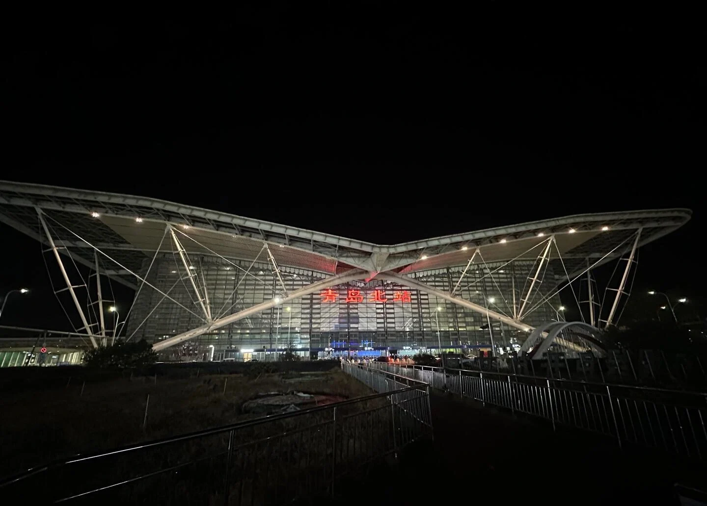 Night view of Qingdao North Railway Station with modern glass facade and glowing red signage - Where to Stay in Qingdao: Best Areas & Hotels 2026 - The China Journey Night view of Qingdao North Railway Station with modern glass facade and glowing red signage - Where to Stay in Qingdao: Best Areas & Hotels 2026 - The China Journey