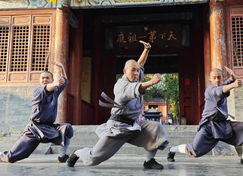 Shaolin Kung Fu performance — Shaolin monks demonstrating traditional martial arts poses in front of the temple courtyard